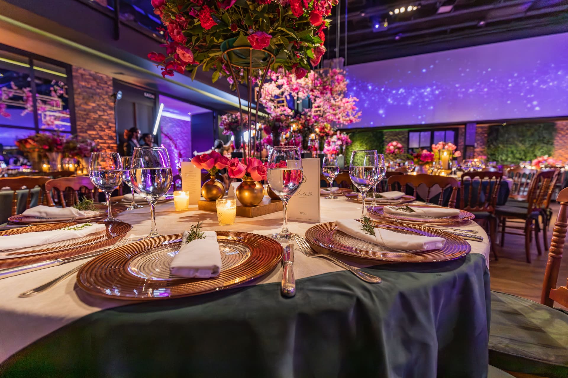 Elegant gala tablescape with tall floral centerpieces, gold chargers, and candlelight